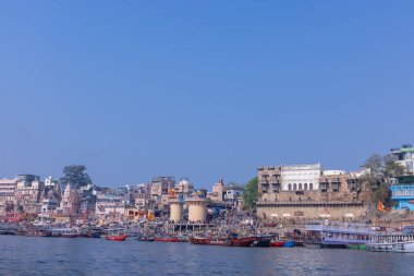Varanasi, Uttar Pradesh, Hindistan - 22 Mart 2024: Varanasi 'deki nehir çetelerinin yakınındaki ghatların mimari görüşü ve tapınakları. Ganga nehrinde yüzen tekneden binaların görüntüsü.