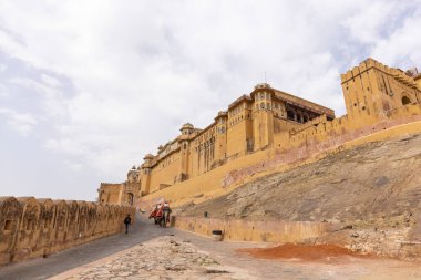 Jaipur 'daki kehribar kalesinde madalyalı file binen kimliği belirsiz bir turist. Arkaplanda Amber Kalesi 'nin mimari görünümü.