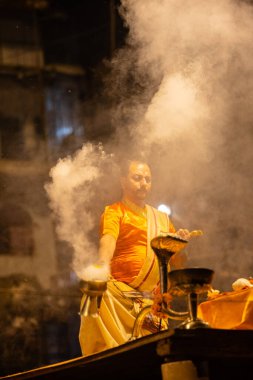 Varanasi, Uttar Pradesh, Hindistan - 21 Mart 2024: Ganga aarti, bir grup genç erkek rahip Assi Ghat 'ta geleneksel Hint ayinleri ile geleneksel elbise giyerek akşam üstü Ganga duası yapıyorlar..