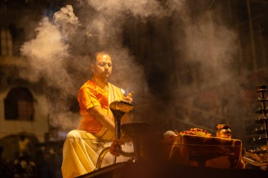 Varanasi, Uttar Pradesh, Hindistan - 21 Mart 2024: Ganga aarti, bir grup genç erkek rahip Assi Ghat 'ta geleneksel Hint ayinleri ile geleneksel elbise giyerek akşam üstü Ganga duası yapıyorlar..