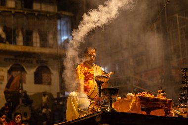 Varanasi, Uttar Pradesh, Hindistan - 21 Mart 2024: Ganga aarti, bir grup genç erkek rahip Assi Ghat 'ta geleneksel Hint ayinleri ile geleneksel elbise giyerek akşam üstü Ganga duası yapıyorlar..
