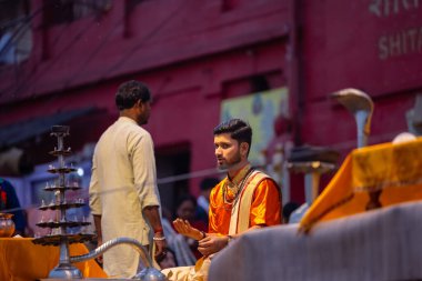 Varanasi, Uttar Pradesh, Hindistan - 21 Mart 2024: Ganga aarti, bir grup genç erkek rahip Assi Ghat 'ta geleneksel Hint ayinleri ile geleneksel elbise giyerek akşam üstü Ganga duası yapıyorlar..