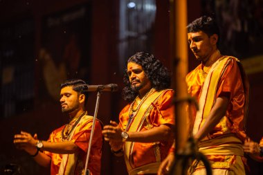 Varanasi, Uttar Pradesh, Hindistan - 21 Mart 2024: Ganga aarti, bir grup genç erkek rahip Assi Ghat 'ta geleneksel Hint ayinleri ile geleneksel elbise giyerek akşam üstü Ganga duası yapıyorlar..