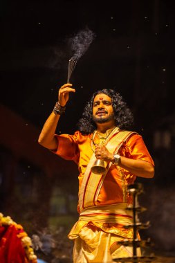 Varanasi, Uttar Pradesh, Hindistan - 21 Mart 2024: Ganga aarti, bir grup genç erkek rahip Assi Ghat 'ta geleneksel Hint ayinleri ile geleneksel elbise giyerek akşam üstü Ganga duası yapıyorlar..