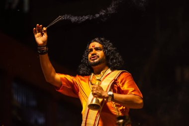 Varanasi, Uttar Pradesh, Hindistan - 21 Mart 2024: Ganga aarti, bir grup genç erkek rahip Assi Ghat 'ta geleneksel Hint ayinleri ile geleneksel elbise giyerek akşam üstü Ganga duası yapıyorlar..