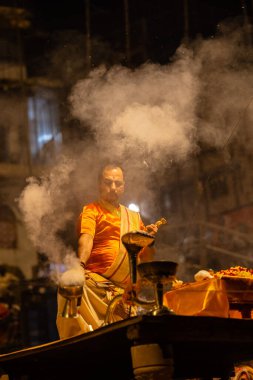 Varanasi, Uttar Pradesh, Hindistan - 21 Mart 2024: Ganga aarti, bir grup genç erkek rahip Assi Ghat 'ta geleneksel Hint ayinleri ile geleneksel elbise giyerek akşam üstü Ganga duası yapıyorlar..