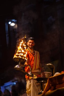 Varanasi, Uttar Pradesh, Hindistan - 21 Mart 2024: Ganga aarti, bir grup genç erkek rahip Assi Ghat 'ta geleneksel Hint ayinleri ile geleneksel elbise giyerek akşam üstü Ganga duası yapıyorlar..