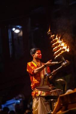 Varanasi, Uttar Pradesh, Hindistan - 21 Mart 2024: Ganga aarti, bir grup genç erkek rahip Assi Ghat 'ta geleneksel Hint ayinleri ile geleneksel elbise giyerek akşam üstü Ganga duası yapıyorlar..