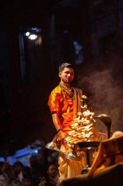 Varanasi, Uttar Pradesh, Hindistan - 21 Mart 2024: Ganga aarti, bir grup genç erkek rahip Assi Ghat 'ta geleneksel Hint ayinleri ile geleneksel elbise giyerek akşam üstü Ganga duası yapıyorlar..
