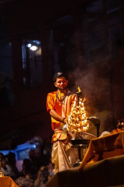 Varanasi, Uttar Pradesh, Hindistan - 21 Mart 2024: Ganga aarti, bir grup genç erkek rahip Assi Ghat 'ta geleneksel Hint ayinleri ile geleneksel elbise giyerek akşam üstü Ganga duası yapıyorlar..