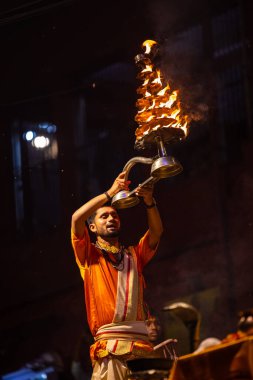 Varanasi, Uttar Pradesh, Hindistan - 21 Mart 2024: Ganga aarti, bir grup genç erkek rahip Assi Ghat 'ta geleneksel Hint ayinleri ile geleneksel elbise giyerek akşam üstü Ganga duası yapıyorlar..