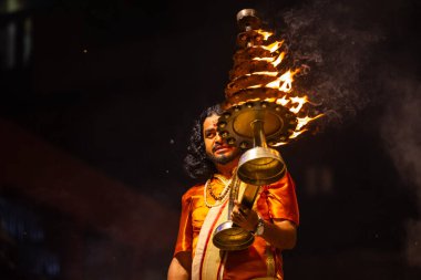 Varanasi, Uttar Pradesh, Hindistan - 21 Mart 2024: Ganga aarti, bir grup genç erkek rahip Assi Ghat 'ta geleneksel Hint ayinleri ile geleneksel elbise giyerek akşam üstü Ganga duası yapıyorlar..