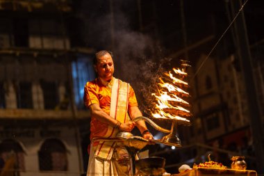Varanasi, Uttar Pradesh, Hindistan - 21 Mart 2024: Ganga aarti, bir grup genç erkek rahip Assi Ghat 'ta geleneksel Hint ayinleri ile geleneksel elbise giyerek akşam üstü Ganga duası yapıyorlar..