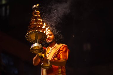 Varanasi, Uttar Pradesh, Hindistan - 21 Mart 2024: Ganga aarti, bir grup genç erkek rahip Assi Ghat 'ta geleneksel Hint ayinleri ile geleneksel elbise giyerek akşam üstü Ganga duası yapıyorlar..