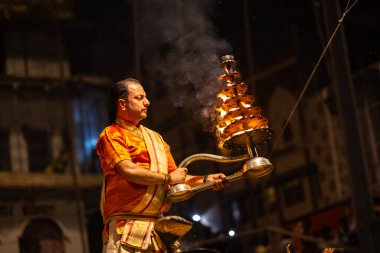 Varanasi, Uttar Pradesh, Hindistan - 21 Mart 2024: Ganga aarti, bir grup genç erkek rahip Assi Ghat 'ta geleneksel Hint ayinleri ile geleneksel elbise giyerek akşam üstü Ganga duası yapıyorlar..