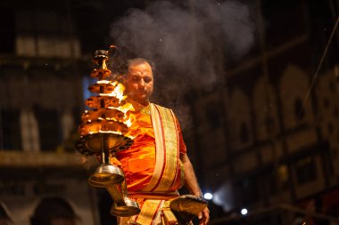 Varanasi, Uttar Pradesh, Hindistan - 21 Mart 2024: Ganga aarti, bir grup genç erkek rahip Assi Ghat 'ta geleneksel Hint ayinleri ile geleneksel elbise giyerek akşam üstü Ganga duası yapıyorlar..
