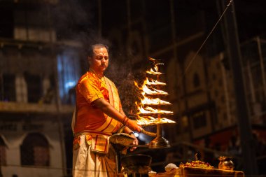 Varanasi, Uttar Pradesh, Hindistan - 21 Mart 2024: Ganga aarti, bir grup genç erkek rahip Assi Ghat 'ta geleneksel Hint ayinleri ile geleneksel elbise giyerek akşam üstü Ganga duası yapıyorlar..
