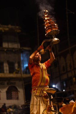 Varanasi, Uttar Pradesh, Hindistan - 21 Mart 2024: Ganga aarti, bir grup genç erkek rahip Assi Ghat 'ta geleneksel Hint ayinleri ile geleneksel elbise giyerek akşam üstü Ganga duası yapıyorlar..