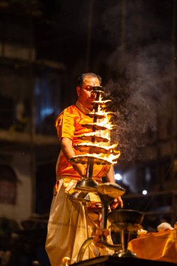 Varanasi, Uttar Pradesh, Hindistan - 21 Mart 2024: Ganga aarti, bir grup genç erkek rahip Assi Ghat 'ta geleneksel Hint ayinleri ile geleneksel elbise giyerek akşam üstü Ganga duası yapıyorlar..