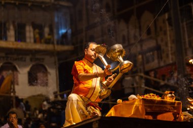 Varanasi, Uttar Pradesh, Hindistan - 21 Mart 2024: Ganga aarti, bir grup genç erkek rahip Assi Ghat 'ta geleneksel Hint ayinleri ile geleneksel elbise giyerek akşam üstü Ganga duası yapıyorlar..