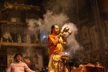 Varanasi, Uttar Pradesh, Hindistan - 21 Mart 2024: Ganga aarti, bir grup genç erkek rahip Assi Ghat 'ta geleneksel Hint ayinleri ile geleneksel elbise giyerek akşam üstü Ganga duası yapıyorlar..