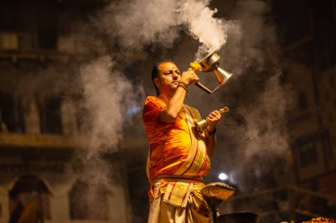 Varanasi, Uttar Pradesh, Hindistan - 21 Mart 2024: Ganga aarti, bir grup genç erkek rahip Assi Ghat 'ta geleneksel Hint ayinleri ile geleneksel elbise giyerek akşam üstü Ganga duası yapıyorlar..