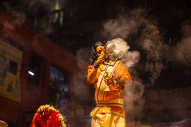 Varanasi, Uttar Pradesh, Hindistan - 21 Mart 2024: Ganga aarti, bir grup genç erkek rahip Assi Ghat 'ta geleneksel Hint ayinleri ile geleneksel elbise giyerek akşam üstü Ganga duası yapıyorlar..