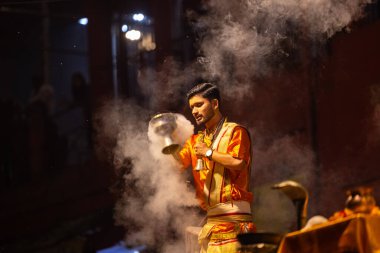 Varanasi, Uttar Pradesh, Hindistan - 21 Mart 2024: Ganga aarti, bir grup genç erkek rahip Assi Ghat 'ta geleneksel Hint ayinleri ile geleneksel elbise giyerek akşam üstü Ganga duası yapıyorlar..