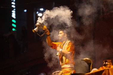 Varanasi, Uttar Pradesh, Hindistan - 21 Mart 2024: Ganga aarti, bir grup genç erkek rahip Assi Ghat 'ta geleneksel Hint ayinleri ile geleneksel elbise giyerek akşam üstü Ganga duası yapıyorlar..