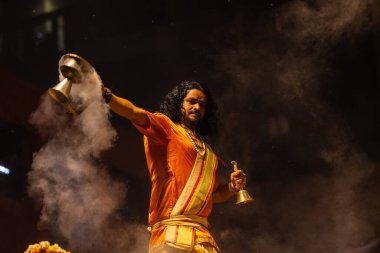 Varanasi, Uttar Pradesh, Hindistan - 21 Mart 2024: Ganga aarti, bir grup genç erkek rahip Assi Ghat 'ta geleneksel Hint ayinleri ile geleneksel elbise giyerek akşam üstü Ganga duası yapıyorlar..