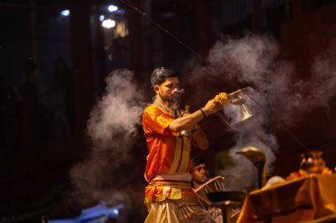 Varanasi, Uttar Pradesh, Hindistan - 21 Mart 2024: Ganga aarti, bir grup genç erkek rahip Assi Ghat 'ta geleneksel Hint ayinleri ile geleneksel elbise giyerek akşam üstü Ganga duası yapıyorlar..