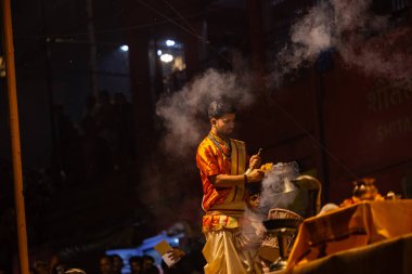Varanasi, Uttar Pradesh, Hindistan - 21 Mart 2024: Ganga aarti, bir grup genç erkek rahip Assi Ghat 'ta geleneksel Hint ayinleri ile geleneksel elbise giyerek akşam üstü Ganga duası yapıyorlar..