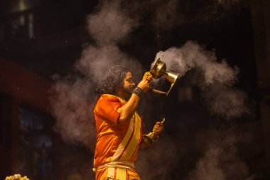 Varanasi, Uttar Pradesh, Hindistan - 21 Mart 2024: Ganga aarti, bir grup genç erkek rahip Assi Ghat 'ta geleneksel Hint ayinleri ile geleneksel elbise giyerek akşam üstü Ganga duası yapıyorlar..