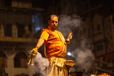 Varanasi, Uttar Pradesh, Hindistan - 21 Mart 2024: Ganga aarti, bir grup genç erkek rahip Assi Ghat 'ta geleneksel Hint ayinleri ile geleneksel elbise giyerek akşam üstü Ganga duası yapıyorlar..