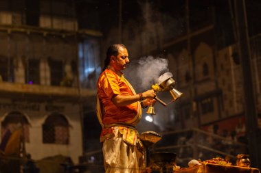 Varanasi, Uttar Pradesh, Hindistan - 21 Mart 2024: Ganga aarti, bir grup genç erkek rahip Assi Ghat 'ta geleneksel Hint ayinleri ile geleneksel elbise giyerek akşam üstü Ganga duası yapıyorlar..