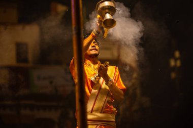 Varanasi, Uttar Pradesh, Hindistan - 21 Mart 2024: Ganga aarti, bir grup genç erkek rahip Assi Ghat 'ta geleneksel Hint ayinleri ile geleneksel elbise giyerek akşam üstü Ganga duası yapıyorlar..
