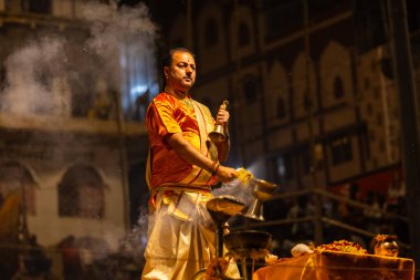 Varanasi, Uttar Pradesh, Hindistan - 21 Mart 2024: Ganga aarti, bir grup genç erkek rahip Assi Ghat 'ta geleneksel Hint ayinleri ile geleneksel elbise giyerek akşam üstü Ganga duası yapıyorlar..
