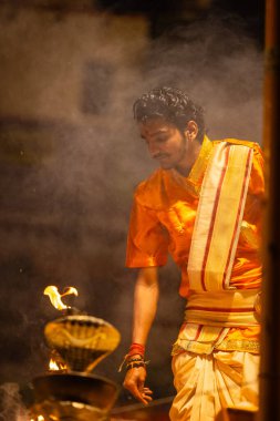 Varanasi, Uttar Pradesh, Hindistan - 21 Mart 2024: Ganga aarti, bir grup genç erkek rahip Assi Ghat 'ta geleneksel Hint ayinleri ile geleneksel elbise giyerek akşam üstü Ganga duası yapıyorlar..