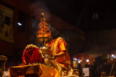 Varanasi, Uttar Pradesh, Hindistan - 21 Mart 2024: Ganga aarti, bir grup genç erkek rahip Assi Ghat 'ta geleneksel Hint ayinleri ile geleneksel elbise giyerek akşam üstü Ganga duası yapıyorlar..