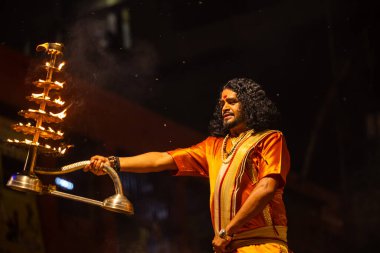 Varanasi, Uttar Pradesh, Hindistan - 21 Mart 2024: Ganga aarti, bir grup genç erkek rahip Assi Ghat 'ta geleneksel Hint ayinleri ile geleneksel elbise giyerek akşam üstü Ganga duası yapıyorlar..