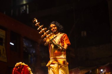 Varanasi, Uttar Pradesh, Hindistan - 21 Mart 2024: Ganga aarti, bir grup genç erkek rahip Assi Ghat 'ta geleneksel Hint ayinleri ile geleneksel elbise giyerek akşam üstü Ganga duası yapıyorlar..