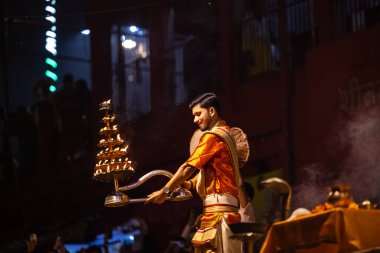 Varanasi, Uttar Pradesh, Hindistan - 21 Mart 2024: Ganga aarti, bir grup genç erkek rahip Assi Ghat 'ta geleneksel Hint ayinleri ile geleneksel elbise giyerek akşam üstü Ganga duası yapıyorlar..