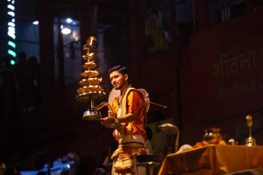 Varanasi, Uttar Pradesh, Hindistan - 21 Mart 2024: Ganga aarti, bir grup genç erkek rahip Assi Ghat 'ta geleneksel Hint ayinleri ile geleneksel elbise giyerek akşam üstü Ganga duası yapıyorlar..