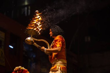 Varanasi, Uttar Pradesh, Hindistan - 21 Mart 2024: Ganga aarti, bir grup genç erkek rahip Assi Ghat 'ta geleneksel Hint ayinleri ile geleneksel elbise giyerek akşam üstü Ganga duası yapıyorlar..