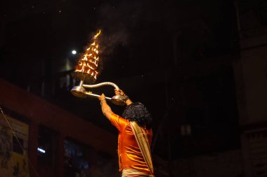Varanasi, Uttar Pradesh, Hindistan - 21 Mart 2024: Ganga aarti, bir grup genç erkek rahip Assi Ghat 'ta geleneksel Hint ayinleri ile geleneksel elbise giyerek akşam üstü Ganga duası yapıyorlar..