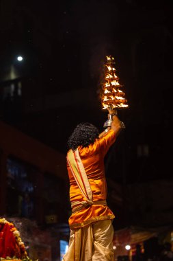Varanasi, Uttar Pradesh, Hindistan - 21 Mart 2024: Ganga aarti, bir grup genç erkek rahip Assi Ghat 'ta geleneksel Hint ayinleri ile geleneksel elbise giyerek akşam üstü Ganga duası yapıyorlar..