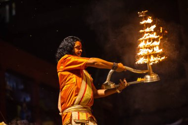 Varanasi, Uttar Pradesh, Hindistan - 21 Mart 2024: Ganga aarti, bir grup genç erkek rahip Assi Ghat 'ta geleneksel Hint ayinleri ile geleneksel elbise giyerek akşam üstü Ganga duası yapıyorlar..
