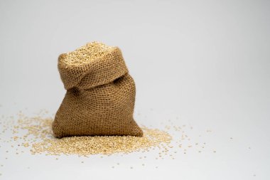 Beyaz arkaplanlı küçük kahverengi bir çuval bezinde beyaz Qinua tohumları