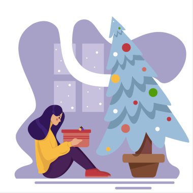 Noel ağacı hediye kutusunun yanında oturan bir kız. Kız bir Noel hediyesini açıyor. Yeni yıl ya da Noel konsepti