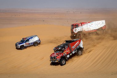 SAUDI ARABIA -  5TH-17TH JANUARY, 2020: 42nd Dakar Rally from Jeddah to Riyad. Trucks and car climbing the dunes. clipart